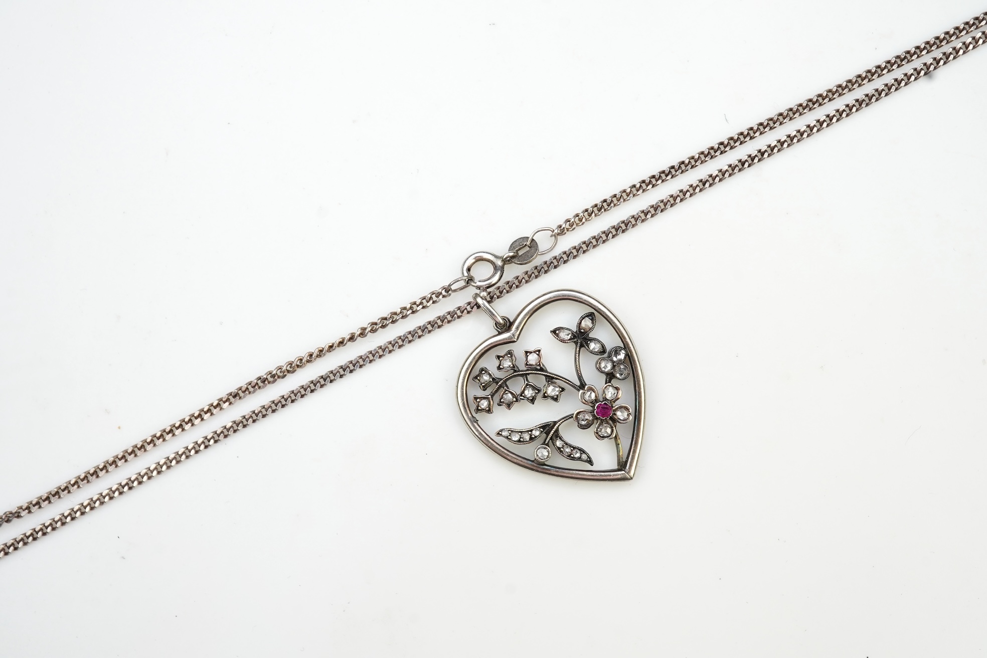 A diamond pendant, designed as a spray of flowers in a heart-shaped frame, set with rose-cut diamonds and a circular-cut ruby, to a later silver chain, pendant 3.1cm, chain length 44cm